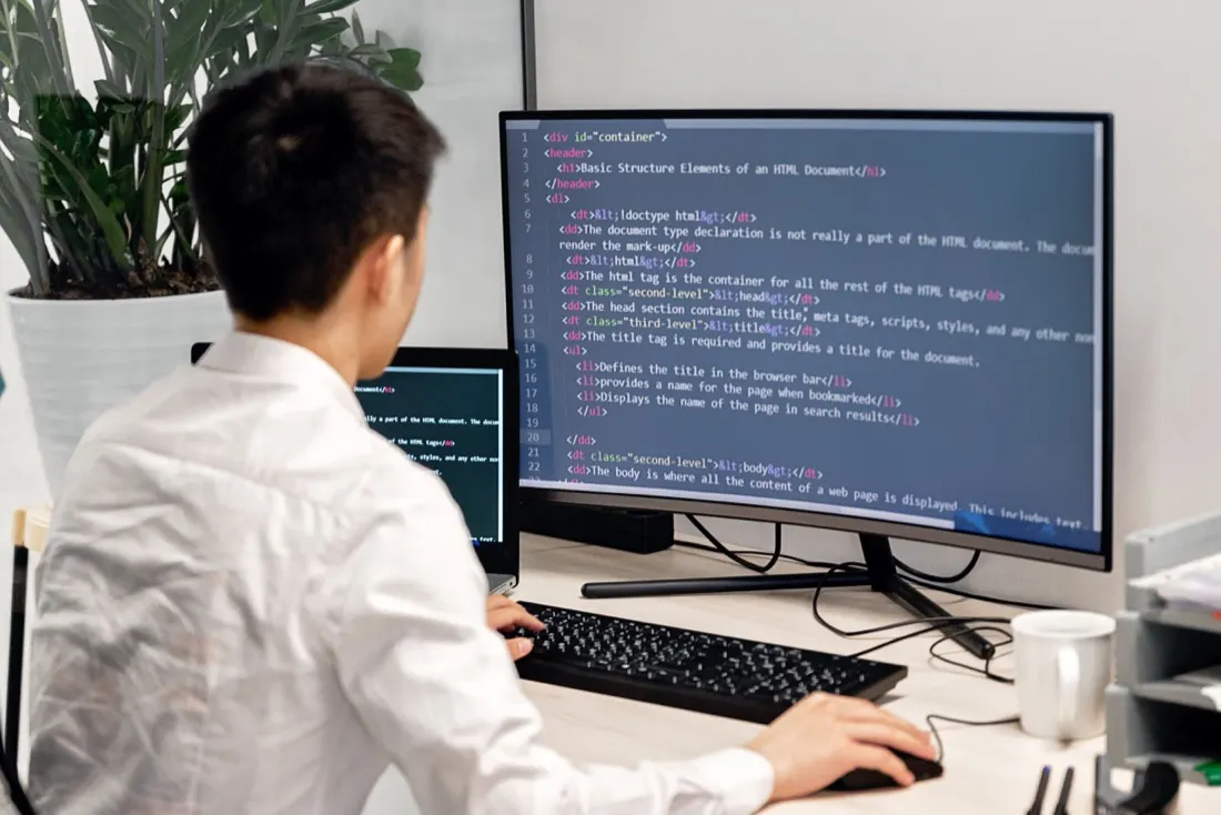 Software engineer building custom business applications on dual monitors